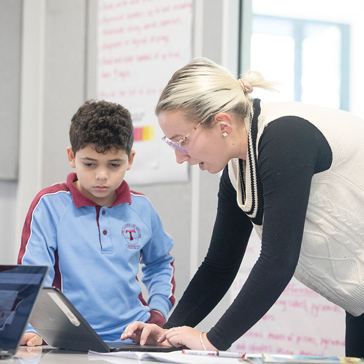 A teacher helping her student on the laptop at St Bernadette's Primary School Dundas Valley