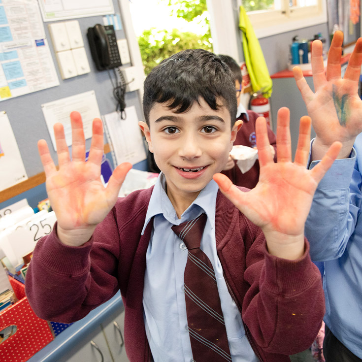 Student showing his painted covered hands after art class at St Bernadette's Primary School Dundas Valley