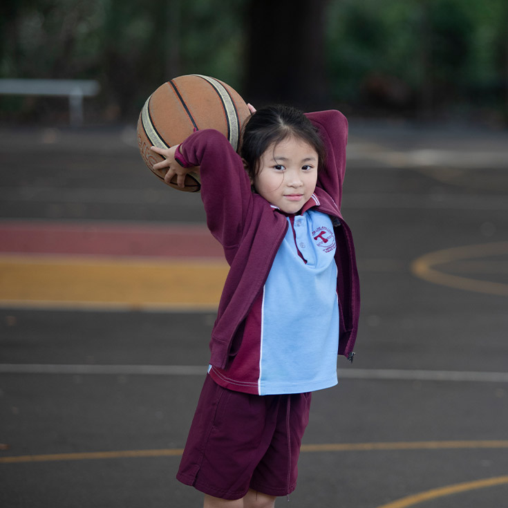 Student playing basketball on the basketball court at St Bernadette's Primary School Dundas Valley