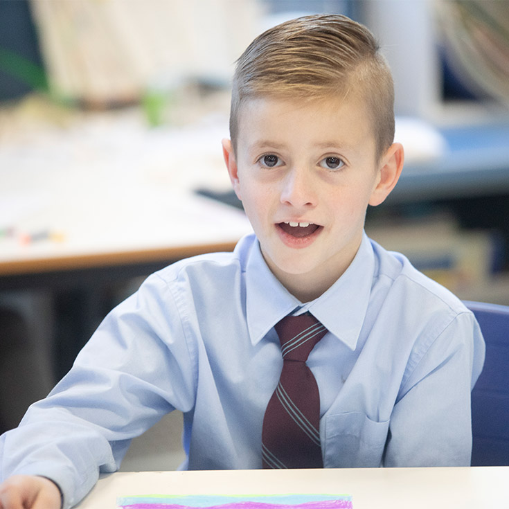 Student smiling at his desk in the classroom at St Bernadette's Primary School Dundas Valley